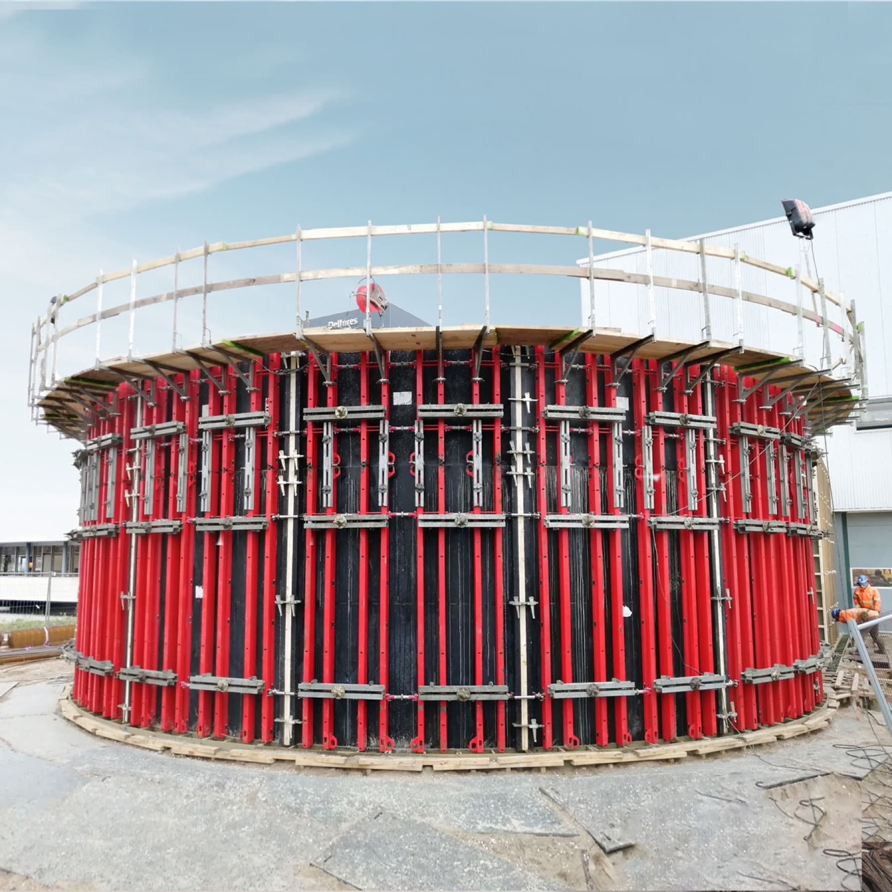 Curved steel formwork panels, walers and strongbacks bolted around a circular concrete tank